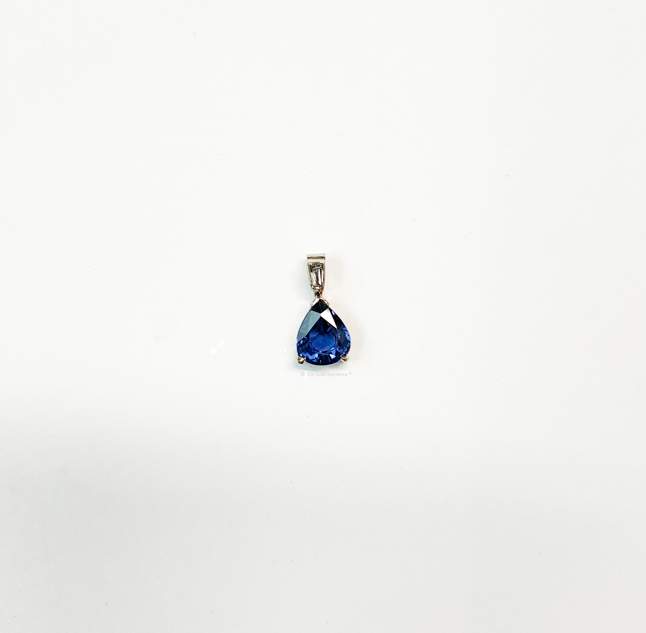 White gold pendant with pear drop sapphire and tapered diamond